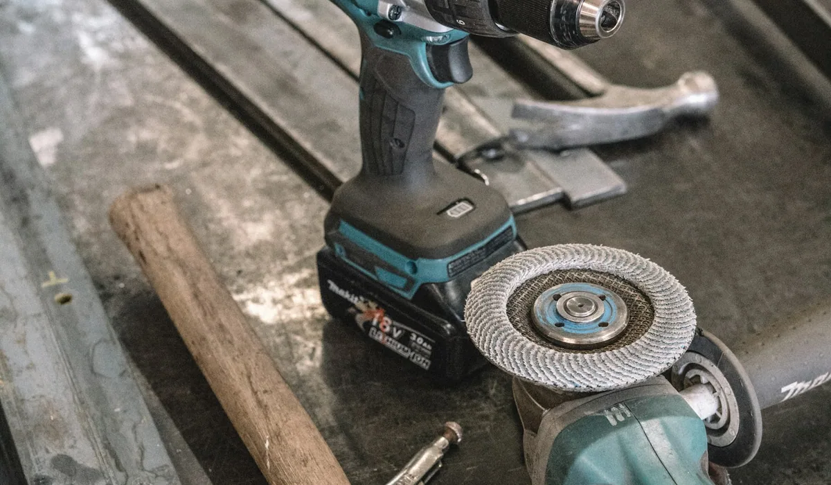 A cordless drill next to an angle grinder on a workbench - heavier kit for shops that have outgrown a one-truck workflow.