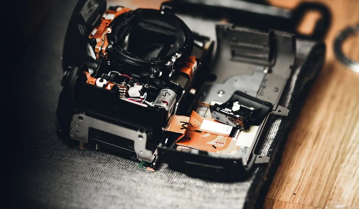 A film SLR camera disassembled on a repair bench showing internal mechanisms