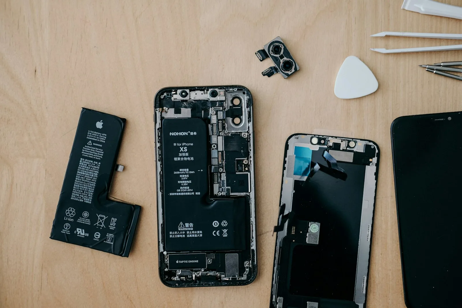 Repair technician working on the internal motherboard of a smartphone at a workbench, illustrating the hands-on nature of phone repair work